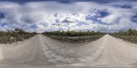 a wide angle view of a dirt track with a cloudy sky background and the camera on the left side of it