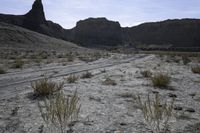 a dirt road is shown in front of an eroded mountain slope with the trail in the middle