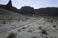 a dirt road is shown in front of an eroded mountain slope with the trail in the middle