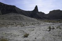 a dirt road is shown in front of an eroded mountain slope with the trail in the middle