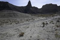 a dirt road is shown in front of an eroded mountain slope with the trail in the middle