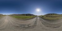 the sun is shining brightly over a dirt road near grassy hills and grass hills, with two cars in it