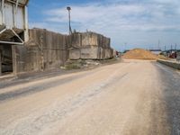 a dirt road passing through a factory near a building under construction in the area above ground