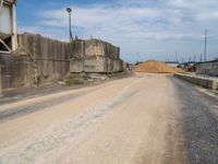 a dirt road passing through a factory near a building under construction in the area above ground