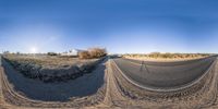 this is a panoramic view of the dirt road at an intersection with a barn in the background