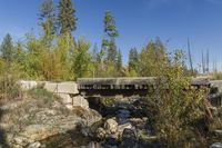 small bridge with many rocks and trees in the background area as well as blue sky