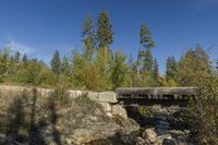 small bridge with many rocks and trees in the background area as well as blue sky