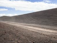 a white motorcycle is parked along the side of a dirt road in front of a hill