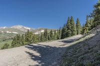 a dirt road runs down the side of a mountain range and into an valley below