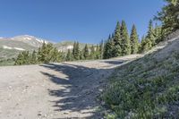 a dirt road runs down the side of a mountain range and into an valley below