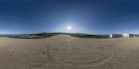 360 - angle view of a dirt road near a beach with a building and water in the background