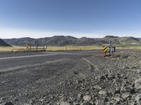 the roadway is empty on both sides of the desert as there are mountains in the distance