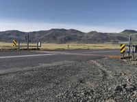 the roadway is empty on both sides of the desert as there are mountains in the distance