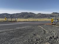 the roadway is empty on both sides of the desert as there are mountains in the distance