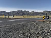 the roadway is empty on both sides of the desert as there are mountains in the distance