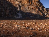 a man with his dog sitting on the ground outside of an open area near rocks