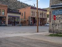 a red fire hydrant sitting in front of an old store window and building next to an open air field