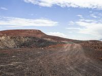 a dirt road that has a white stop sign on it by a hill of rocks