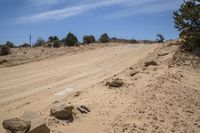 the dirt road is empty but there is no cars on it in the desert on a sunny day