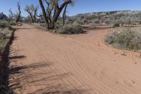 this is an image of a dirt road in the desert during the day with clouds