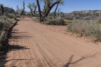 this is an image of a dirt road in the desert during the day with clouds