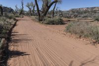 this is an image of a dirt road in the desert during the day with clouds