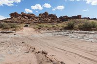 an suv that is driving on some dirt in the dirt path through a desert area