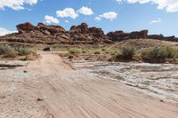 an suv that is driving on some dirt in the dirt path through a desert area