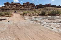 an suv that is driving on some dirt in the dirt path through a desert area