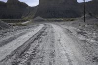 an empty dirt road passes across the desert plain, with large buttes in the background