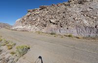 a desert like landscape with large rocks and green plants on the side of a dirt road