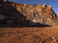 a person with backpack walking on a dirt road through a mountainous terrain, on the way to the summit of a mountain