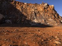 a person with backpack walking on a dirt road through a mountainous terrain, on the way to the summit of a mountain