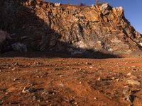 a person with backpack walking on a dirt road through a mountainous terrain, on the way to the summit of a mountain