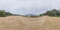 dirt roads are shown by a lake with many trees around it and clouds over them