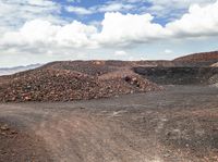 a pile of gravel sits next to some large rocks and gravel hills as the sky looks on