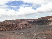 a pile of gravel sits next to some large rocks and gravel hills as the sky looks on