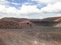 a pile of gravel sits next to some large rocks and gravel hills as the sky looks on