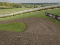 a man riding a bike down a dirt track on a dirt bike ramp next to a green field