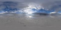 a reflection of the sky and clouds on a beach in front of a mountain range