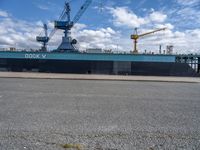 a ship that is in the water at dock with crane above it's head