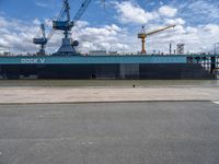 a ship that is in the water at dock with crane above it's head