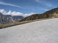 a dog standing in the road near a large mountainous area of land below the mountains