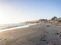 a grassy field by the shore and a cliff with rocks in the ocean in the background