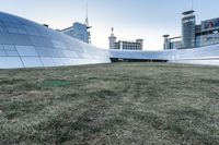 the outside of the building is designed to look like an oculus of architecture with curved metal walls, grass and lawn