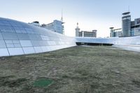 the outside of the building is designed to look like an oculus of architecture with curved metal walls, grass and lawn