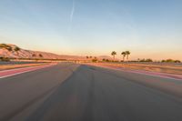 a photo of a dirt race track with sun setting in the distance of the track