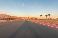 a photo of a dirt race track with sun setting in the distance of the track