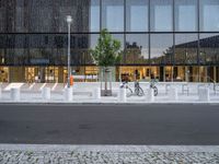 a row of bikes parked next to a tall building next to some steps and trees