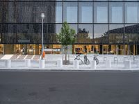 a row of bikes parked next to a tall building next to some steps and trees